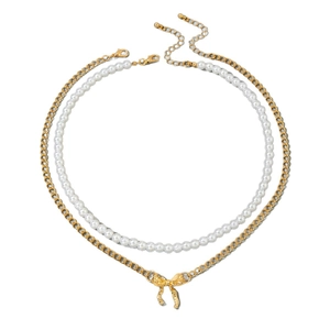 Collier double rang de perles avec un délicat pendentif nœud doré sur fond blanc
