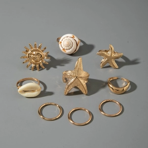 Detail of nine-piece gold alloy ring set featuring ocean starfish and seashell designs