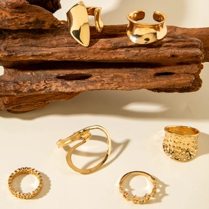 Set of 6 gold irregular geometric rings with textured finish on rustic wood background