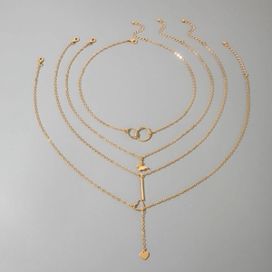 Détail de colliers superposés dorés avec pendentifs papillon, cœur et barre