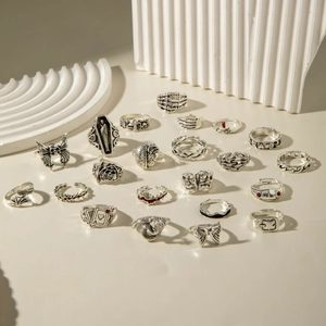 Gothic silver ring set with skull bat and snake designs on stone background