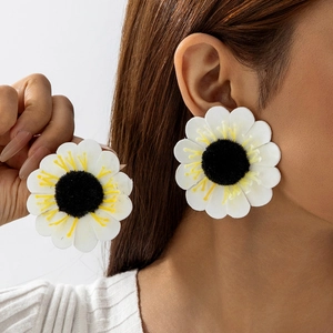 Close-up of oversized white sunflower earrings with layered petals and textured black center