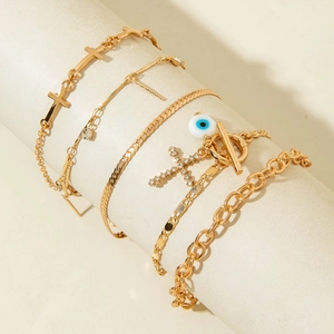 Five-piece gold layered anklet set featuring evil eye pendant and cross charms with OT buckle