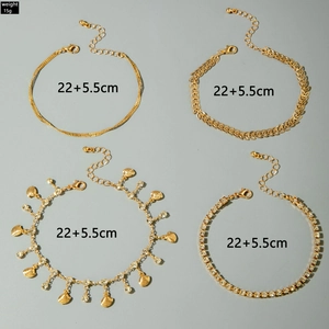 Detail of four-piece gold anklet set with rhinestone charms and leaf textures