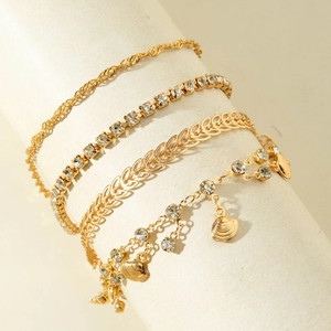 Set of four gold-plated bracelets featuring crystal claw chains and shell charms on a display
