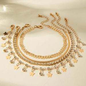 Detail of four-piece gold layered anklet set with butterfly charm and zircon crystals