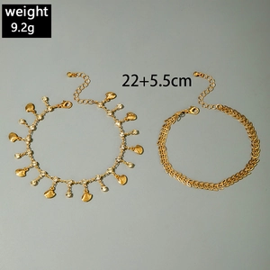 Detail of gold layered anklets with seashell charm, rhinestone accents and leaf chain