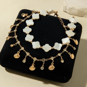 Detail of gold layered anklet with shell pendant and clover beads on black velvet