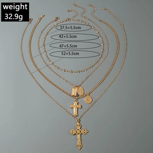 Détail de colliers superposés dorés avec croix et médaillons vintage sur fond gris