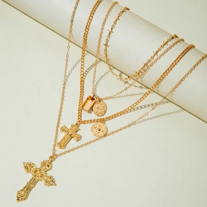 Collier multi-rangs doré avec pendentifs croix et pièces sur un support de présentation