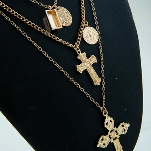 Détail macro de colliers dorés multicouches avec croix sur buste en velours noir