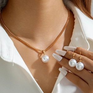 Gros plan sur l'ensemble collier à chaîne dorée et boucles d'oreilles en perles blanches