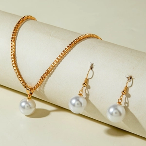 Parure élégante en perles dorées avec collier et boucles d'oreilles sur un support épuré