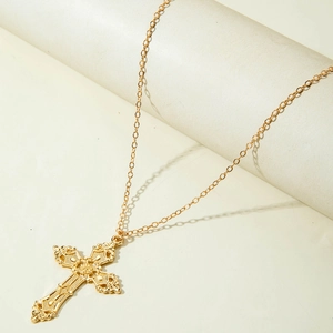 Détail d'un collier pendentif croix dorée avec un design en relief vintage