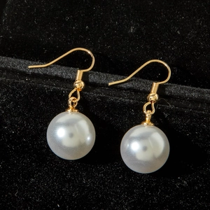 Close-up of elegant pearl drop earrings with gold hooks in a black velvet box