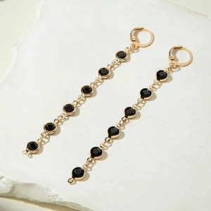 Détails macro de longues boucles d'oreilles dorées à sept strass noirs ronds