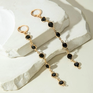 Boucles d'oreilles pendantes dorées avec cristaux noirs sur des blocs de pierre