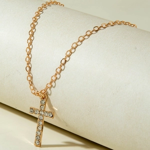 Detailaufnahme der goldfarbenen Kreuz-Halskette mit funkelndem Strass-Besatz im Detail