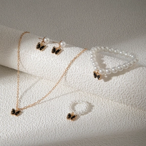 Détail de l'ensemble de bijoux en perles avec breloques papillon en émail noir sur rouleau