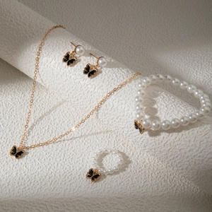 Détail d'une parure de bijoux en perles avec papillons en émail noir et accents dorés