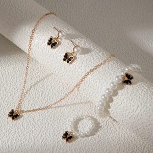 Détail de parure bijoux papillon avec perles, collier doré et accessoires assortis élégants