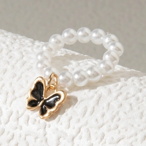 Détail de la bague en perles avec un pendentif papillon en émail noir bordé d'or