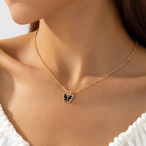 Gros plan d'un élégant collier en chaîne dorée avec pendentif papillon en émail noir