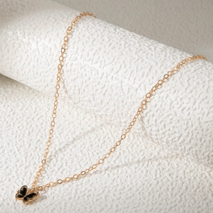 Détail du collier papillon doré avec émail noir et chaîne délicate en métal doré