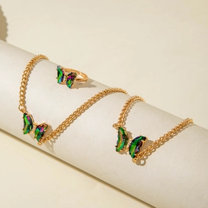 Détail d'un ensemble collier et bague papillon irisé sur des rouleaux crème texturés