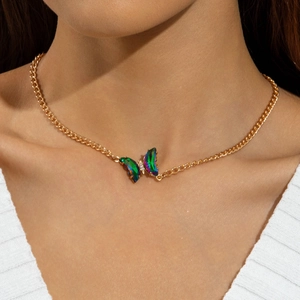 Gros plan du collier papillon doré aux ailes irisées et zircon sur le cou du modèle