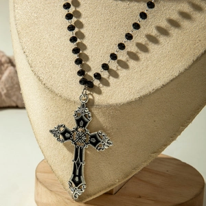 Gothic punk cross pendant necklace with black faceted beads on a beige jewelry display
