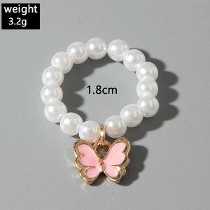 Détail d'une bague en perles avec breloque papillon rose, poids 3,2g et diamètre 1,8cm