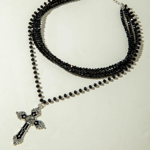 Close-up of beaded multi-layer punk necklace featuring a black cross pendant with baroque details