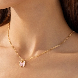 Gros plan d'un collier pendentif papillon rose avec chaîne dorée sur le cou d'un mannequin
