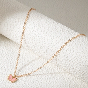 Détail du collier avec pendentif papillon rose émaillé exposé sur un support blanc