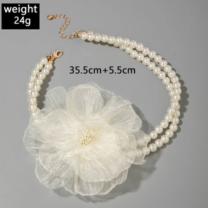 Detailed view of double-layer pearl necklace with a large white fabric flower and gold clasp