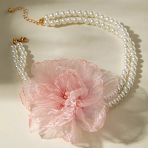 Close-up of a double-layer pearl necklace featuring a large pink organza flower detail