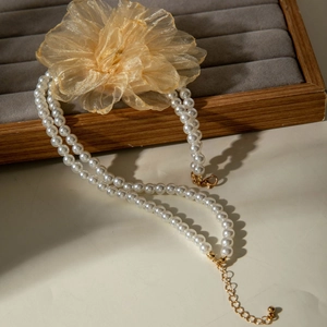 Detail of double-layer pearl necklace with a large gold mesh flower and metal clasp