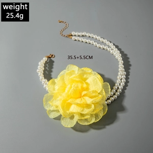 Detailed view of double-layer faux pearl necklace with large yellow fabric flower charm