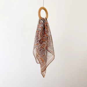 Macro shot of paisley print silk-like chiffon scarf on wooden ring displaying soft texture