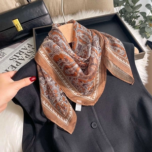Elegant paisley silk-like chiffon scarf in earthy brown tones draped on a wooden hanger