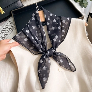 Classic black and white floral paisley silk scarf draped on a wooden hanger with aesthetic props