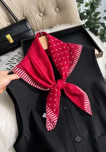 Dettaglio foulard di seta rosso con pois e motivi paisley su un gilet nero elegante