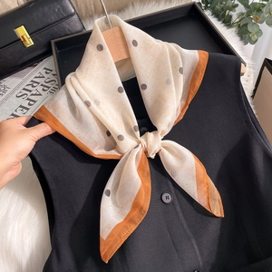Foulard in seta a pois beige e arancione abbinato a un gilet nero stile elegante