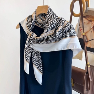 Detail showing elegant silk scarf with Greek key pattern styled on a navy dress