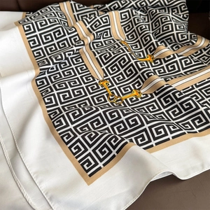 Close-up of elegant silk square scarf with geometric Greek key and golden chain print