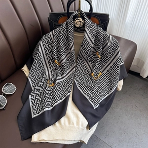 Elegant geometric chain print silk scarf styled on a beige knit top for a luxury look
