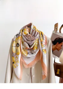 Detail of floral silk scarf styled on a beige blazer with elegant yellow flower patterns
