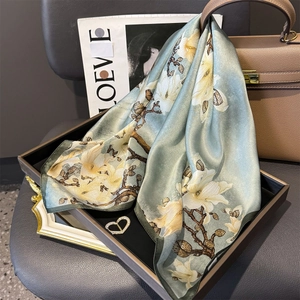 Detail of silk scarf with magnolia prints on luxury handbag and magazine backdrop