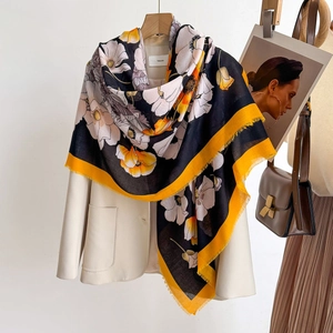 Detailed view of a black floral silk shawl with white flowers and delicate fringe trim